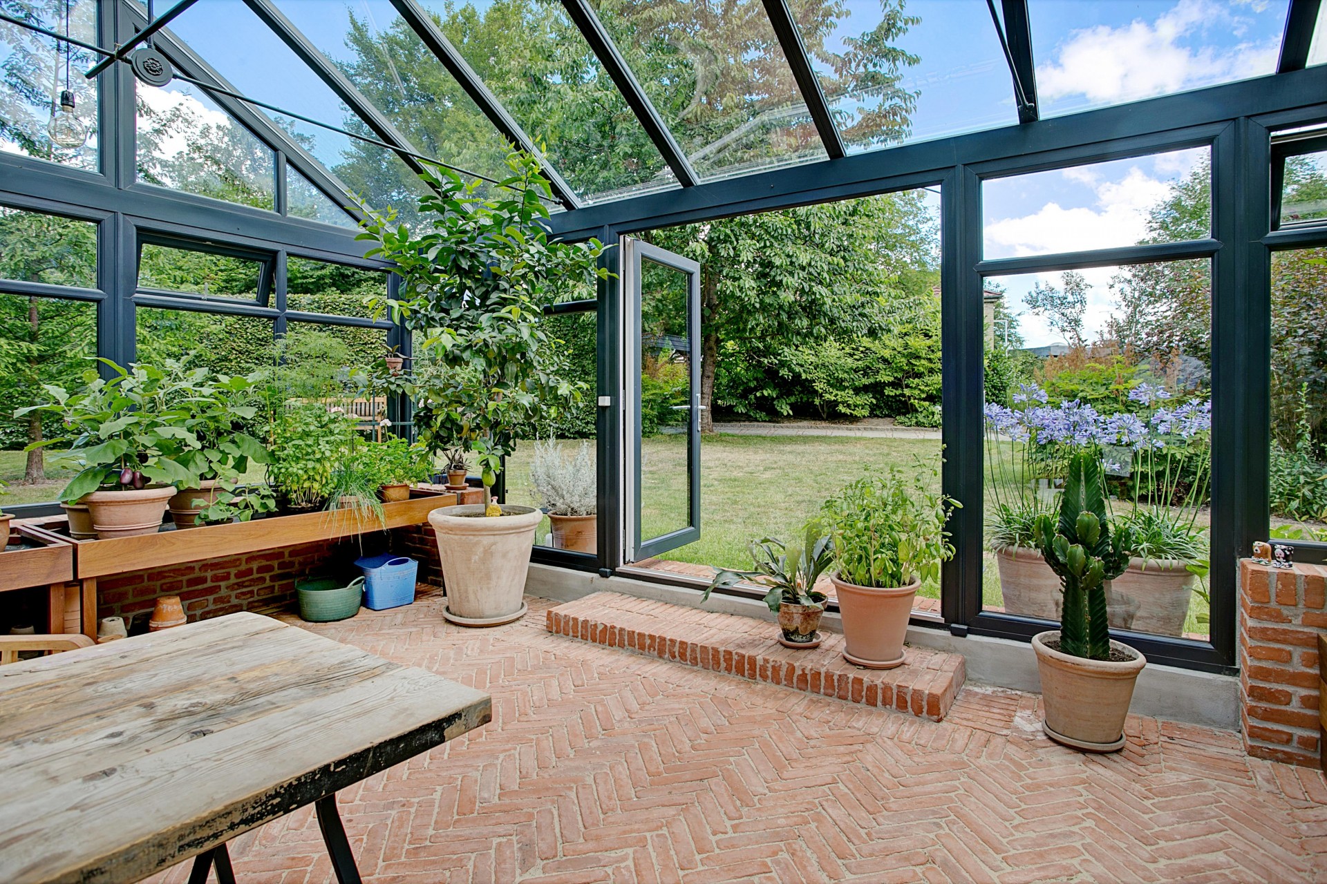 Orangeri med planter og udsigt til haven