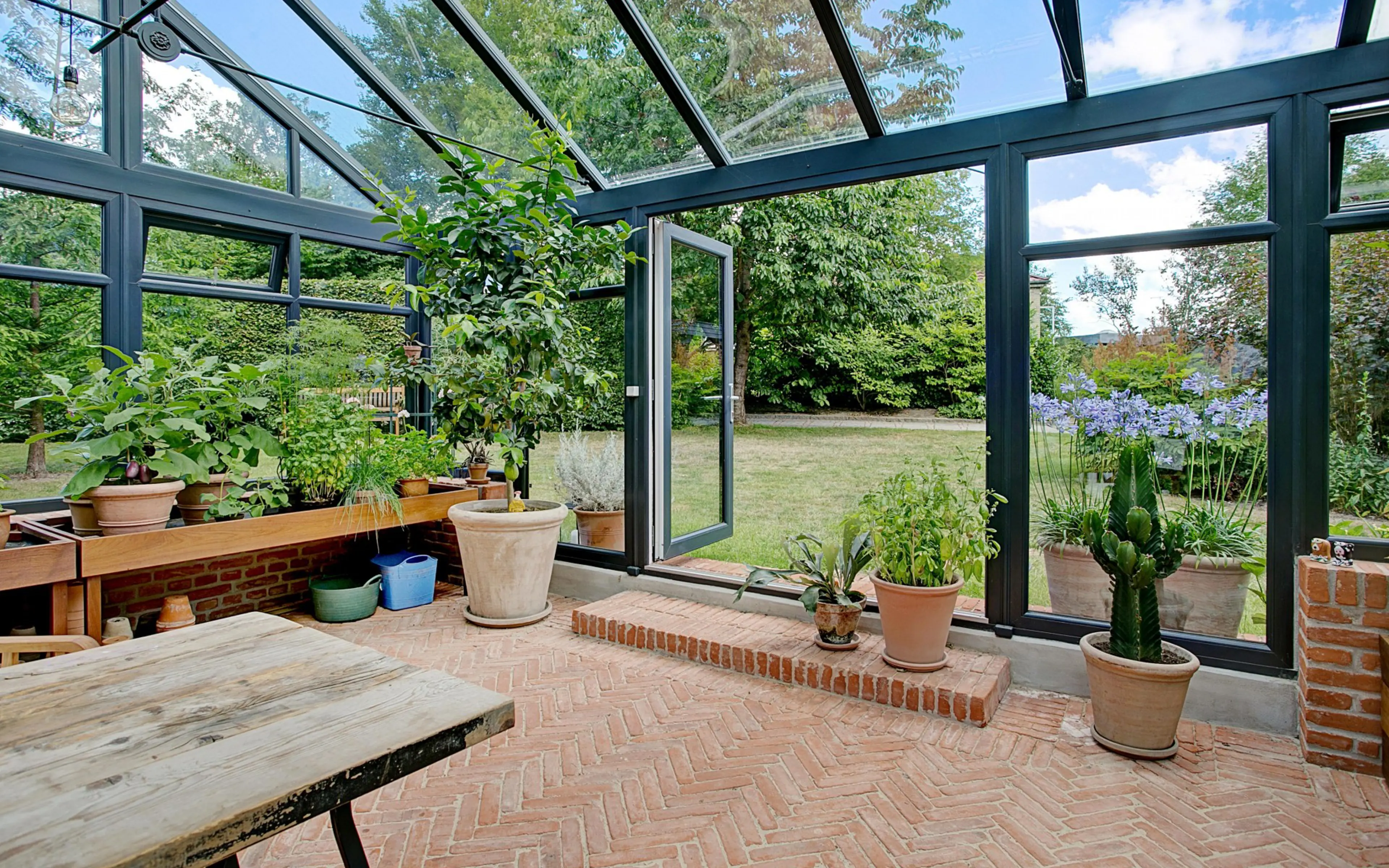 Orangeri med planter og udsigt til haven